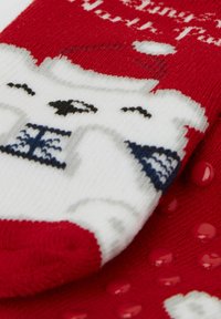 Calzini lavorati a maglia rossi e bianchi con design a orso polare, suola testurizzata con grip in gomma e accenti blu a contrasto.