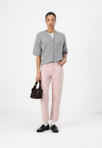 Cardigan grigio corto con maniche corte, jeans rosa a gamba dritta, mocassini neri e una piccola borsa nera. Texture lisce e colori tenui.