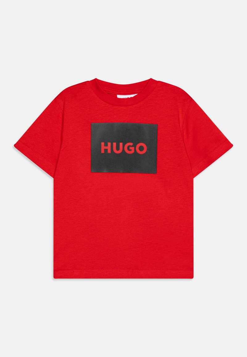 T-shirt en coton rouge avec un graphique rectangulaire noir portant le texte "HUGO" en rouge. Manches courtes et col ras du cou. Texture lisse.