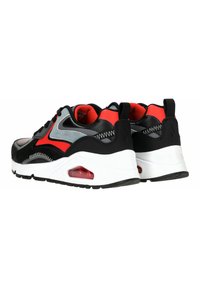 Schwarze und rote Sportschuhe mit einer glatten Oberseite, Mesh-Akzenten, einer weißen Zwischensohle und sichtbarer Luftpolsterung in der Ferse.
