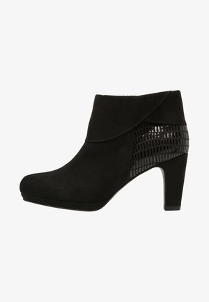 Stivali neri alla caviglia con tomaia in suede e un accento in pelle verniciata texturizzata. Il design include un tacco alto e una punta arrotondata.