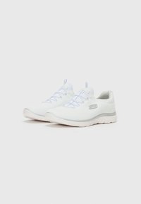 White athletic shoes with a textured fabric upper, elastic laces, a cushioned sole, and a light gray accent along the heel.