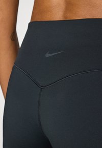 Leggings neri a vita alta realizzati in materiale elastico, con un logo Nike discreto e cuciture flatlock per comfort e durata.