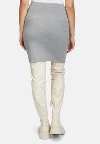 Szara spódnica z prążkowanego dzianiny o dopasowanym kroju, w połączeniu z białymi kozakiem za kolano z zamkami błyskawicznymi i grubymi podeszwami.
