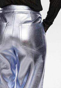 Pantaloni argento metallici con finitura lucida, dotati di due tasche posteriori e un design a vita alta. Tessuto liscio e vestibilità su misura.