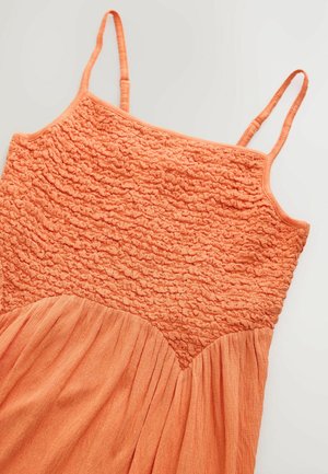 Orange dress with a textured, smocked bodice and flowing skirt. Thin spaghetti straps and gathered detailing at the waist, soft cotton fabric.