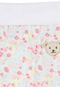 Stoff mit Blumenmuster in Pastellfarben und einem weißen Gummibund. Auf der unteren rechten Ecke befindet sich ein gesticktes Bärengesicht.