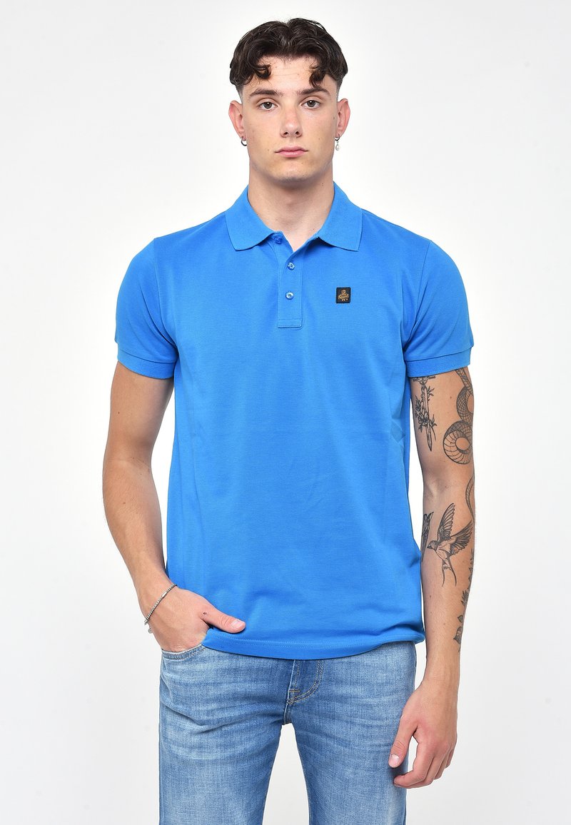 Blaues Poloshirt aus Baumwollstoff mit Kragen und drei Knöpfen. Enthält ein kleines Logo auf der Brust und Kurzärmel. Slim-Fit-Design.