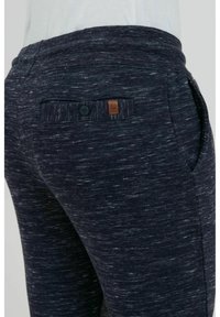 Dark blue textured joggers with a sleek design, featuring a back pocket with a button and a small leather logo patch.
