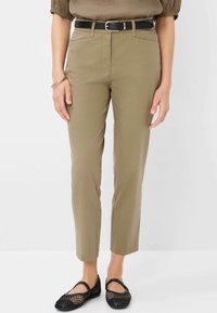 Pantalons khaki à coupe droite, dotés de poches avant, d'une ceinture noire avec une boucle en or, et associés à des ballerines en mesh noires.