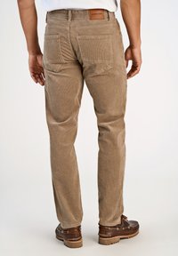 Spodnie z sztruksu w jasnobrązowym kolorze z pionowymi prążkami, z dwoma tylnymi kieszeniami i brązową skórzaną naszywką przy pasie.