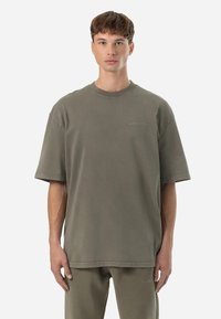 Olive green oversized t-shirt made of soft cotton. Features a crew neckline and subtle logo detail embroidered on the chest.