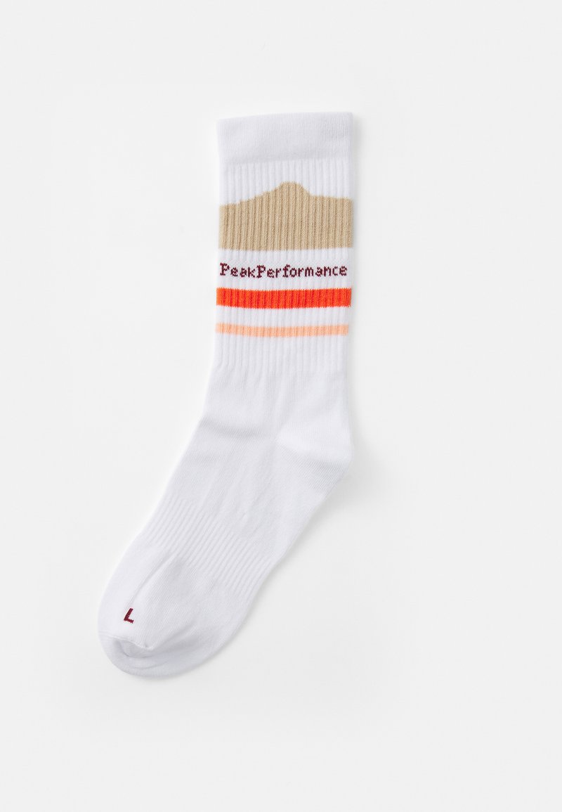 Bijela pletena čarapa s teksturiranim bež i narančastim prugama, s "PeakPerformance" logotipom u crvenoj boji sa strane. Veličina označena na palcu.