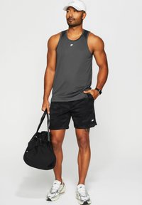 Graues Sport-Top, schwarze Camouflage-Shorts, weiße Kappe, silberne und weiße Sneakers sowie eine schwarze Sporttasche. Glatte Textur, figurbetonter Schnitt.
