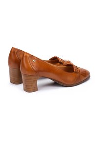Chaussures à talons en cuir marron avec un accent tissé au niveau des orteils et un talon empilé texturé. Forme arrondie et surface lisse.
