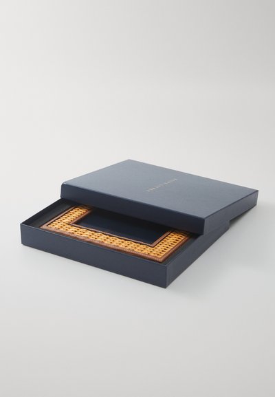 Tumed sinine kast kuldsete tähtedega, milles on ristküliku kujuline fotoraam. Raami ääres on kudumisega vooderdatud rattan ja tume sisematt.