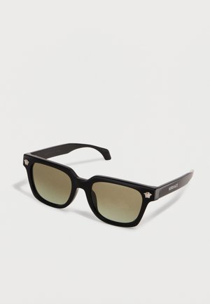 Fekete négyzet alakú keretű Versace napszemüveg fokozatos barna lencsékkel, ezüst Medúza fej logókkal a sarkokon, valamint Versace felirattal a szárakon.