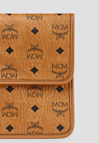 Portefeuille en cuir fauve orné de logos MCM noirs répétés, de formes losanges et de motifs de couronnes de laurier avec des coutures visibles.
