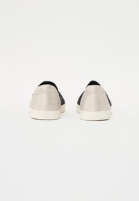 Mustad ja metalliliste hallide sneakerid tekstuuritud mustriga, siledad aktsendid ja valged tallad. Ei ole nähtavaid logosid ega lisafunktsioone.