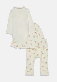 Tvådelad babyklädsel med långärmad vit bodysuit och överdel samt byxor i krämfärgad, prydda med ljusbruna teddybjörnar.