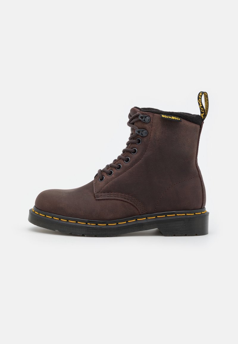 Botte en cuir marron foncé à lacets avec semelle noire, coutures jaunes et une languette avec texte à l'arrière, vue de côté sur fond blanc.