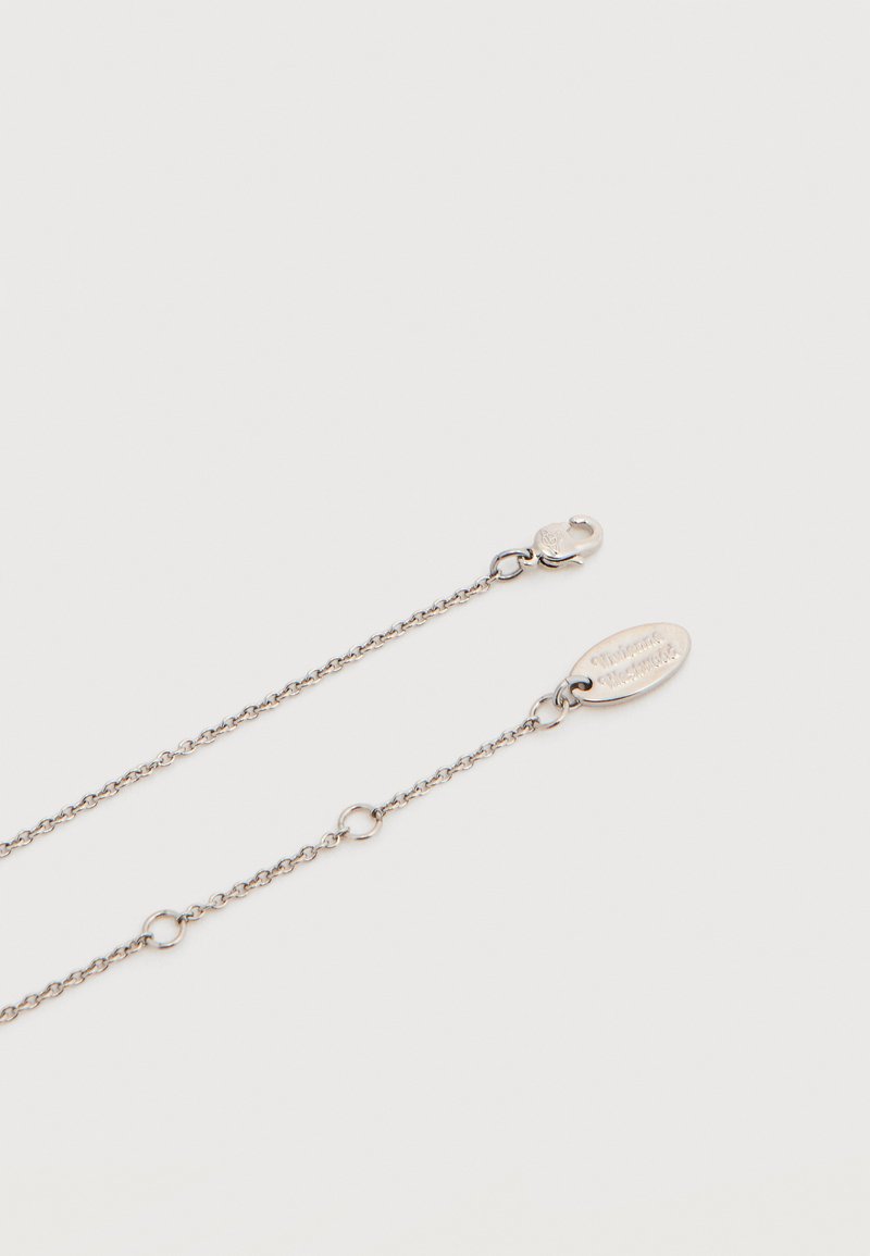 Collar de cadena de plata con un pequeño cierre y una etiqueta ovalada. Presenta eslabones intrincados y acentos circulares a lo largo de su longitud.