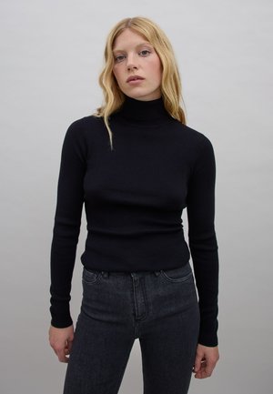 Schwarzer gerippter Rollkragenpullover mit langen Ärmeln, enganliegendem Design und strukturiertem Stoff, getragen mit dunklen Jeans. Neutrale Hintergrund.