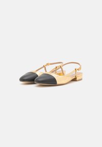 Slingback-lit hanskat, jotka on valmistettu kultaisesta ryppyisestä nahasta ja joissa on musta nahkainen kärki. Vaaleanruskea lohkokorko ja säädettävä hihna istuvuuden parantamiseksi.