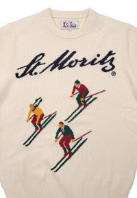 Gebreide trui in crème met tekst "St. Moritz". Voorzien van kleurrijke skiërmotieven in rood, groen en geel tegen groene skipatronen.