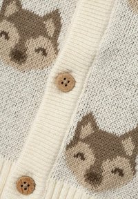Cardigan lavorato a maglia con base crema e motivi di facce di lupo marroni, tessuto testurizzato e bottoni in legno lungo la patta anteriore.
