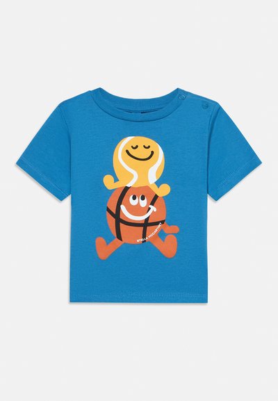 T-shirt bleu à manches courtes pour tout-petit avec une balle de tennis jaune souriante et des personnages de basket-ball orange empilés et marchant.