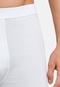 Boxer in cotone bianco con una texture a coste, dotati di un ampio elastico in vita. Il design è aderente e liscio.
