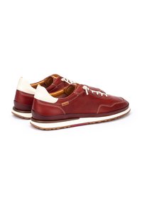 Zapatillas de cuero en rojo oscuro con acentos blancos, diseño de cordones, cuello acolchado y suela de goma en contraste. Acabado de cuero texturizado.