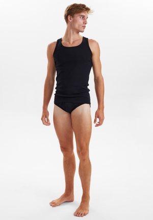 Sort tætsiddende tanktop med rund udskæring, parret med matchende briefs, vist på en stående mandlig model med kort hår.