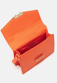 Borsa in pelle arancione dal design strutturato, con chiusura in metallo dorato e interno liscio simile a satin. Etichetta decorativa con logo all'interno.