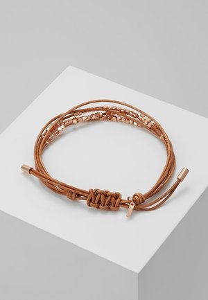 Bracelet en cuir marron enveloppant avec de petites perles métalliques couleur or rose et fermeture à nœud ajustable sur une surface blanche.