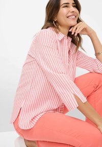 Pink and white striped button-up shirt with three-quarter sleeves, paired with coral pants. Subtle side slits at the hem enhance the design.