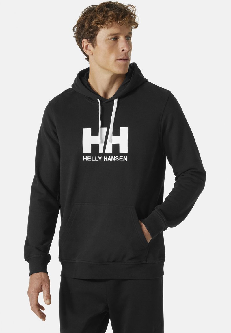 Černá mikina s kapucí vyrobená z materiálu směsi bavlny, která má velké bílé logo "HH" a text "HELly HANSEN". Má přední kapsu a nastavitelné šňůrky na kapuci.