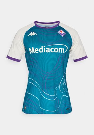 Tyrkysový futbalový dres s bielymi rukávmi, fialovým lemovaním a vlnovým vzorom. V strede je umiestnené logo "Mediacom" a na ľavej strane znak Kappa.