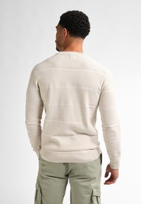 Light beige sweater with a textured, striped pattern. Features a round neck and long sleeves. Worn over green cargo pants.