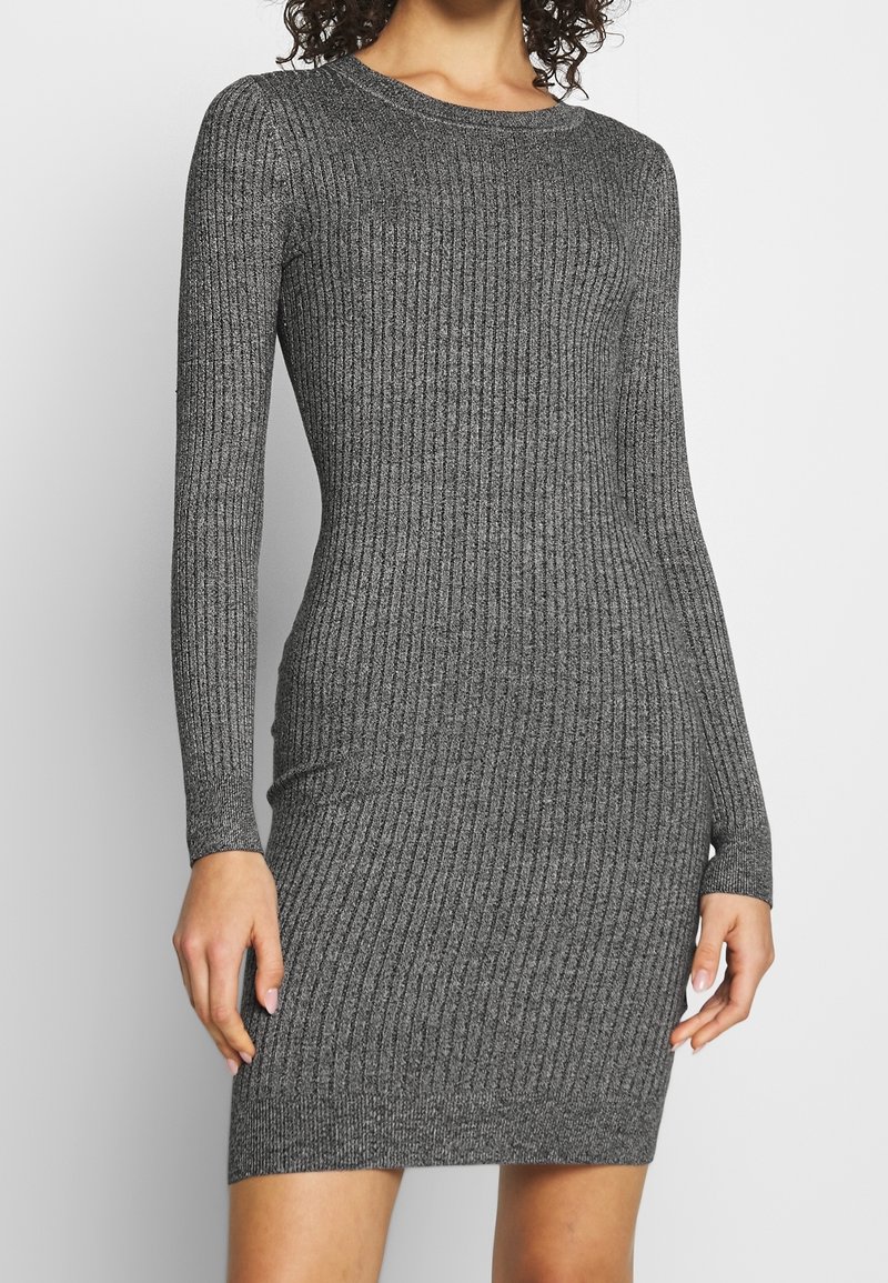 Robe grise à manches longues en tissu côtelé, avec un col rond, une coupe ajustée et un tissu texturé mettant en valeur la silhouette, arrivant au-dessus du genou.