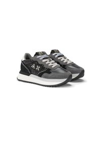 Zapatillas gris y negras que presentan una mezcla de materiales de ante y textil, con una parte superior estampada, suela blanca y cordones en contraste.