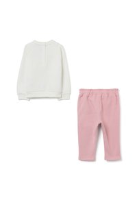 Chemise blanche à manches longues avec trois boutons au dos, associée à un pantalon rose à taille élastique, le tout posé à plat sur un fond blanc.