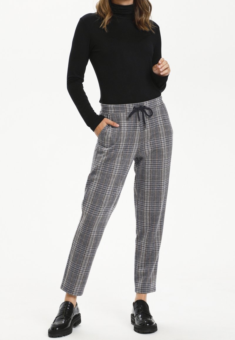 Pantalons à carreaux gris et bleu avec une taille élastique à cordon de serrage, des poches latérales et des jambes fuselées, associés à un haut noir à manches longues.