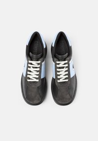 Schwarze und hellblaue Sneaker aus Wildleder und Leder, mit weißen Schnürsenkeln, abgerundetem Zehenbereich und Camper-Logo auf der Zunge.