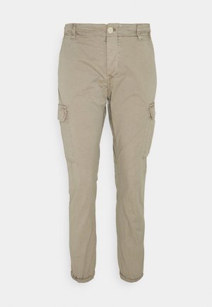 Beige cargobroek met knoopsluiting, zijzakken met flappen en elastische boorden bij de enkels. Gemaakt van een lichte stof.