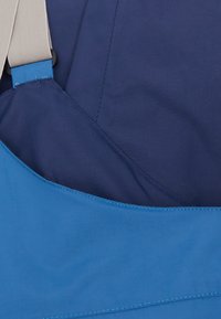 Blauwe stoffen tas met een gladde textuur en een contrasterende marineblauwe voering. Voorzien van een lichtgekleurde band, gestikte randen en een gelaagd ontwerp.