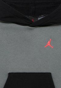 Γκρι φούτερ με μαύρη κουκούλα, τσέπη καγκουρό και μικρό ροζ λογότυπο Jumpman στο στήθος. Υφασμα από μαλακό βαμβακερό μείγμα.