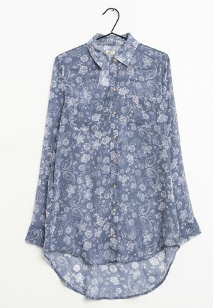 Blauw bloemrijk overhemd met lange mouwen, knopen aan de voorkant, een kraag, voorzakken en een afgeronde zoom, hangend aan een zwarte hanger.