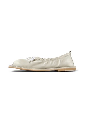 Zapato plano de cuero beige suave con punta redondeada, detalle elástico, lazo blanco de encaje en la parte superior y suela color marrón claro visto desde un lado.